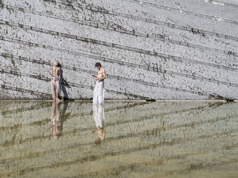 two men near water with a stone backgrounf 