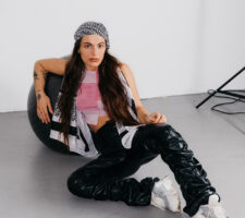 A woman in a bandana sitting on the floor leaning against an exercise ball