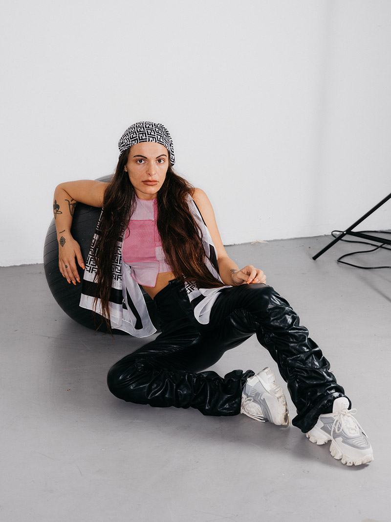 A woman in a bandana sitting on the floor leaning against an exercise ball