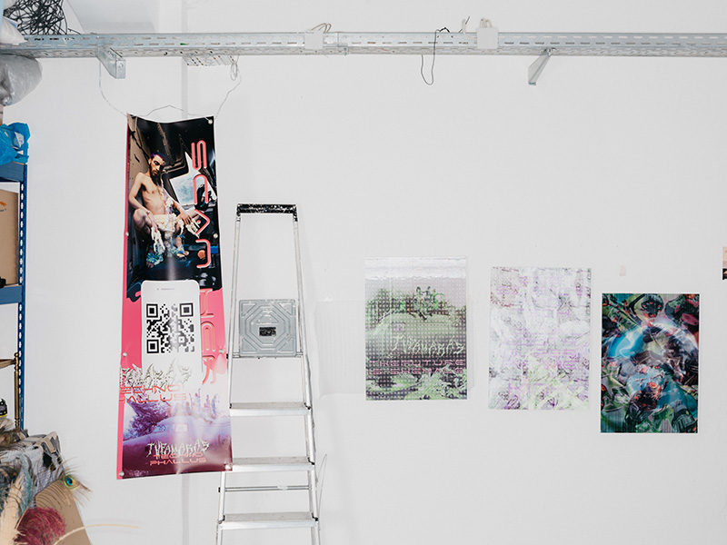 A wall with four pictures hung on it and a ladder leaning against it