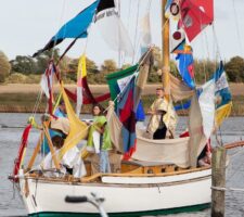 People on an art installation of a boat with colorful fabrics in Arnis, Germany