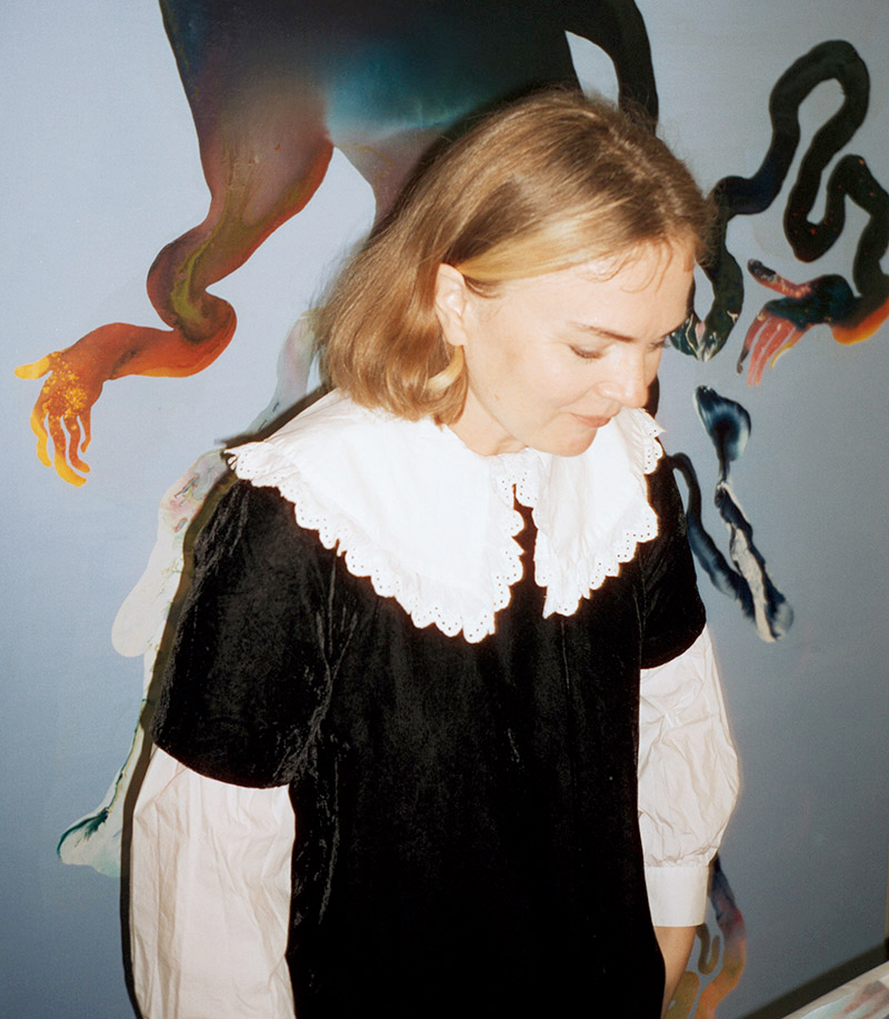 A female artist in front of one of her paintings