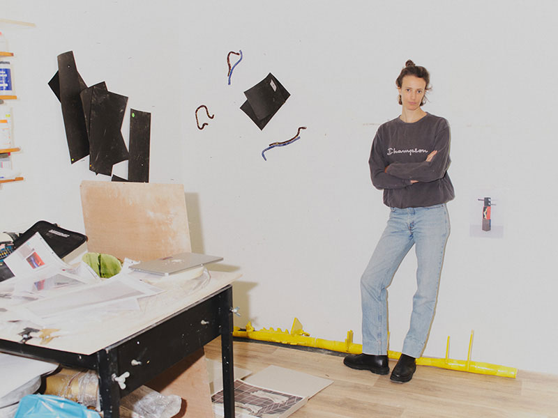 A woman leaning against a white wall