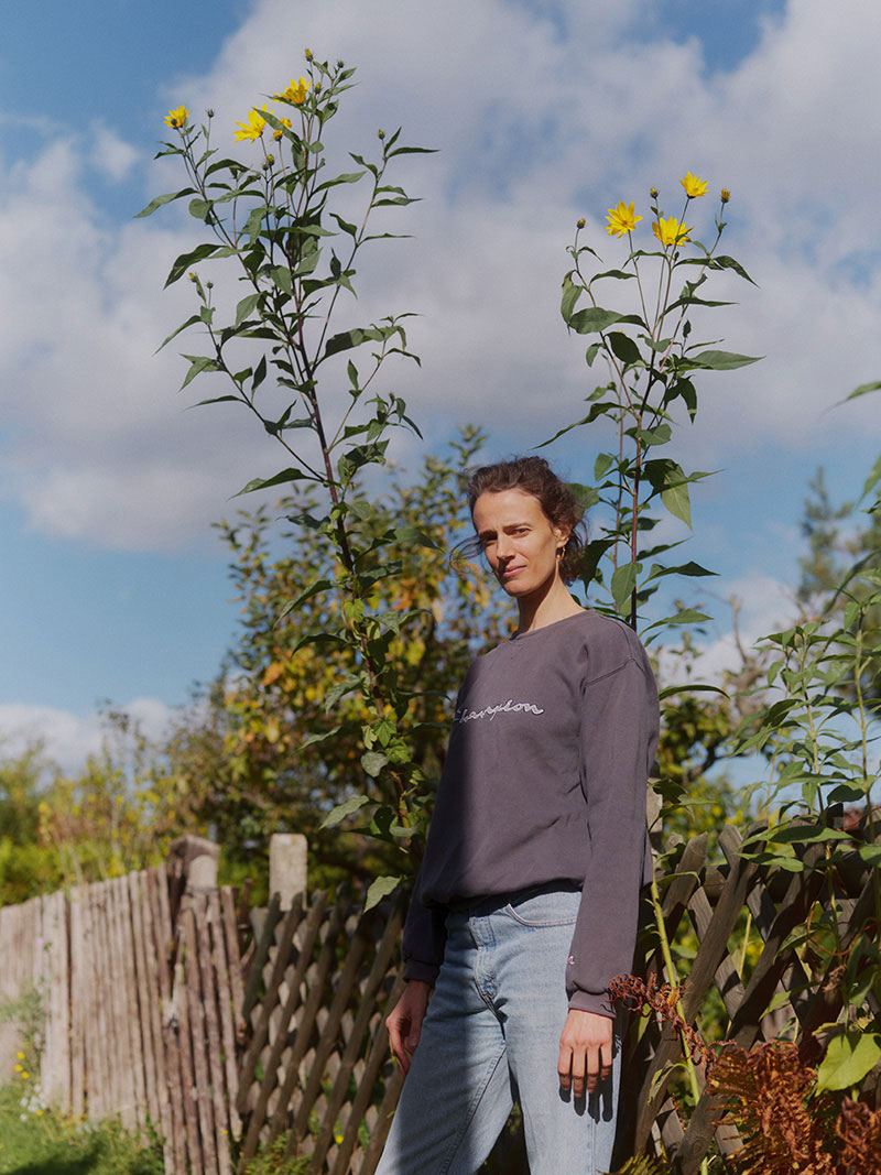 A woman standing in front of tall yellow flowers photographed a little from below