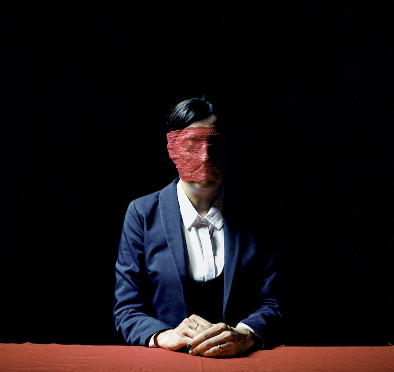 Woman in a suit blindfolded with red lace