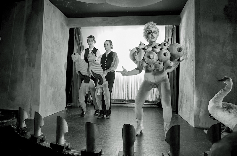 black and white image of Three people on a stage dressed in costumes