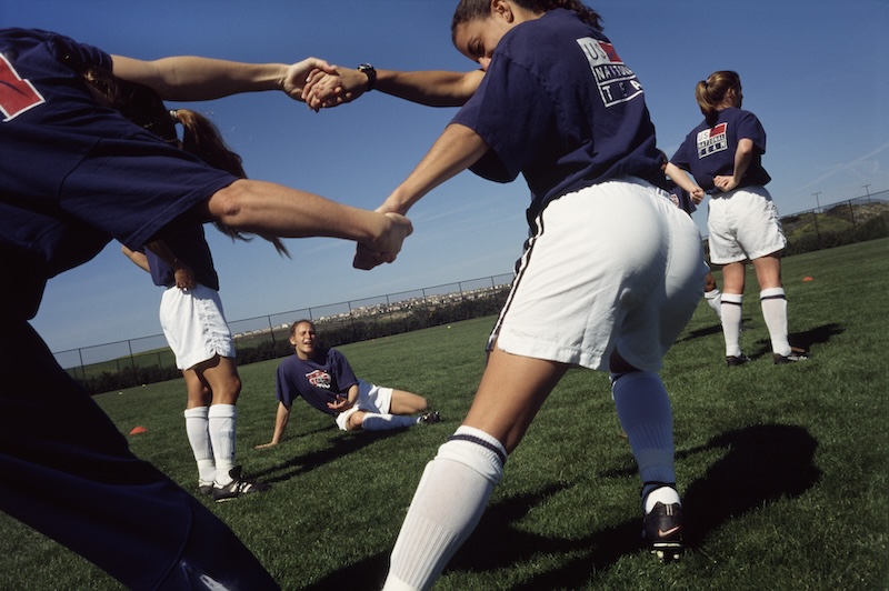 Women soccer players streching outside on a field