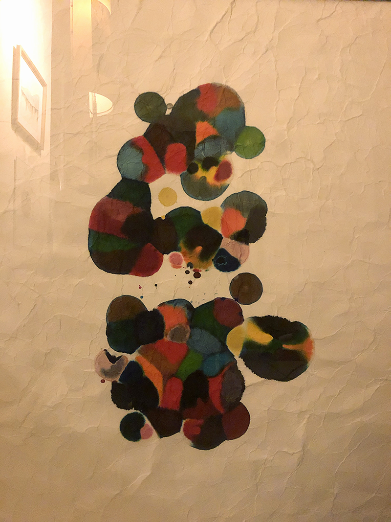 different colored ink bleeds in dots on a textured paper.