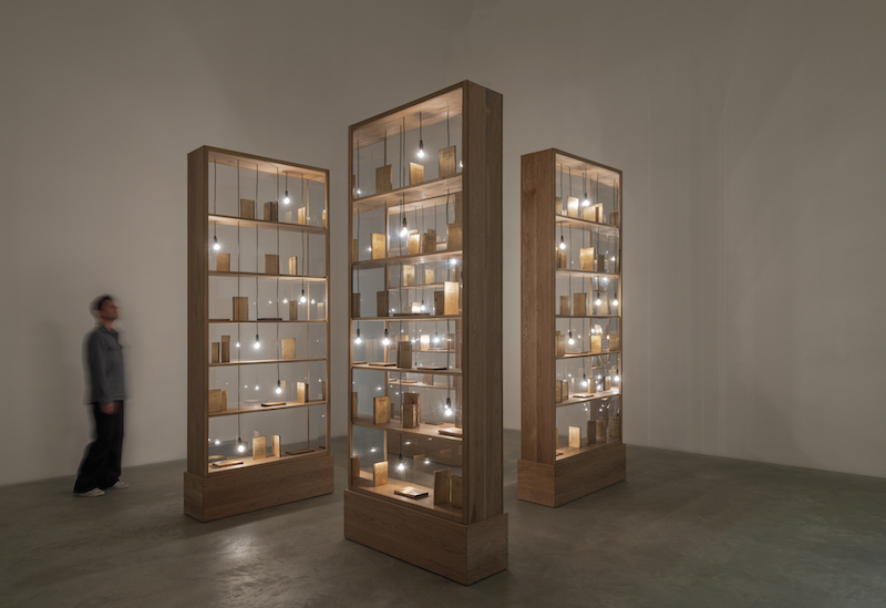 three wooden structures with lights and a visitor 