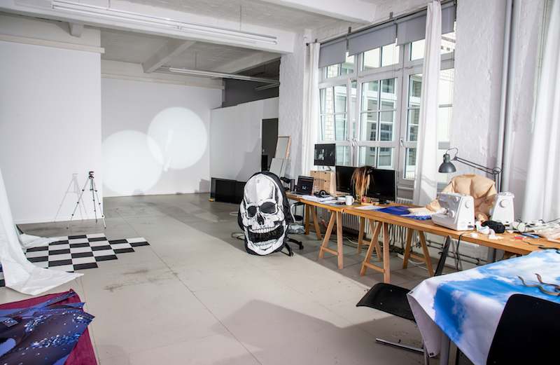 a wide shot of an artist's studio, with tall windows and a long desk