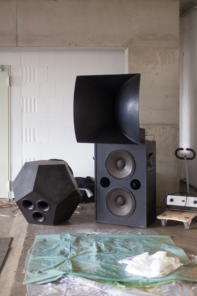 three large speakers in multiple shapes stand against the walls of the studio