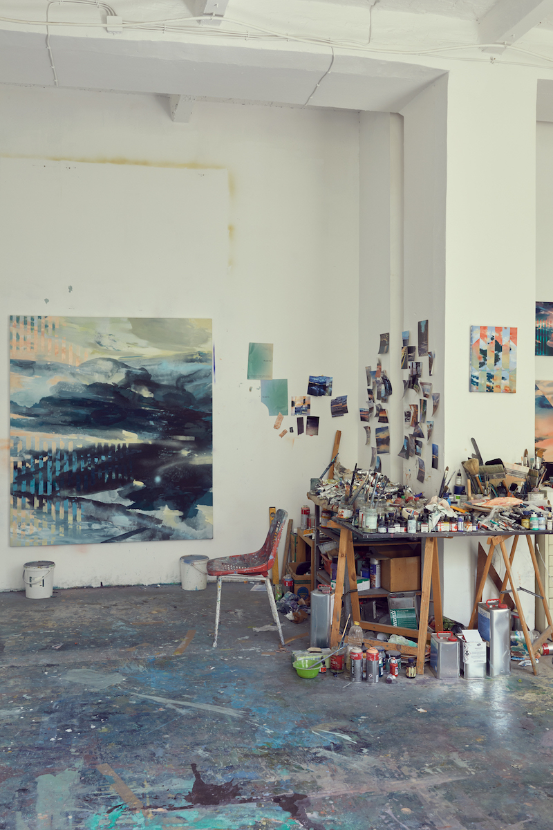 Photograph by Martin Müller of an abstract paintings by Michelle Jezierski hanging on the wall of her studio and a table with art supplies