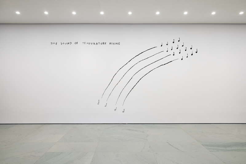 An artwork by Christine Sun Kim, drawn on the white wall of a gallery, reading The Sound of Temperature Rising